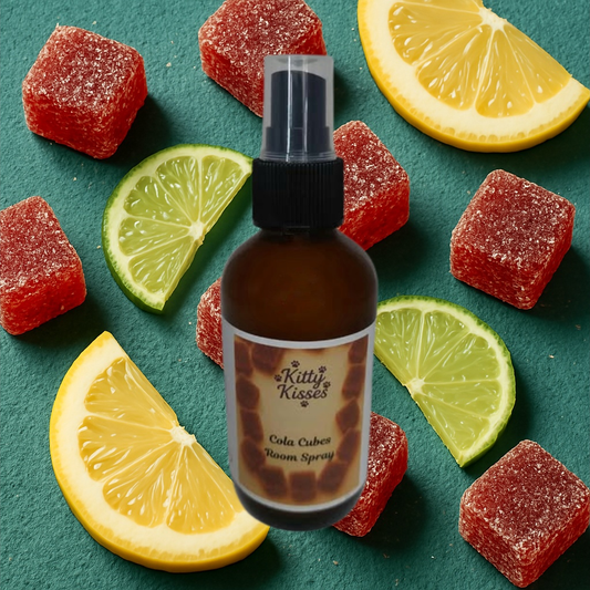 Bottle of Kitty Kisses Cola Cubes roomSpray surrounded by red gummy candies and lemon slices on a green background